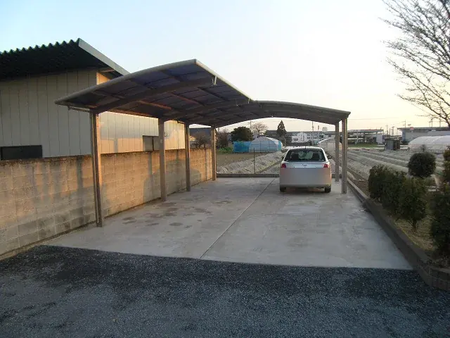 波板屋根のカーポートと、土間コンクリートで仕上げた駐車場